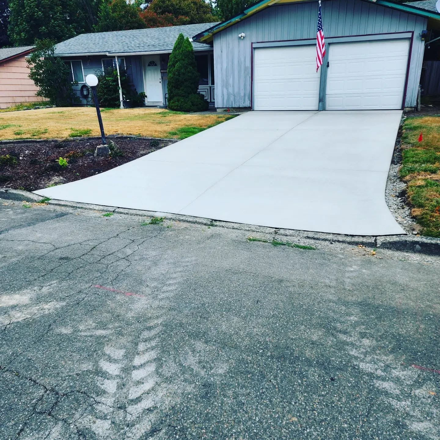 Fresh smooth reinforced concrete driveway after completion with American flag