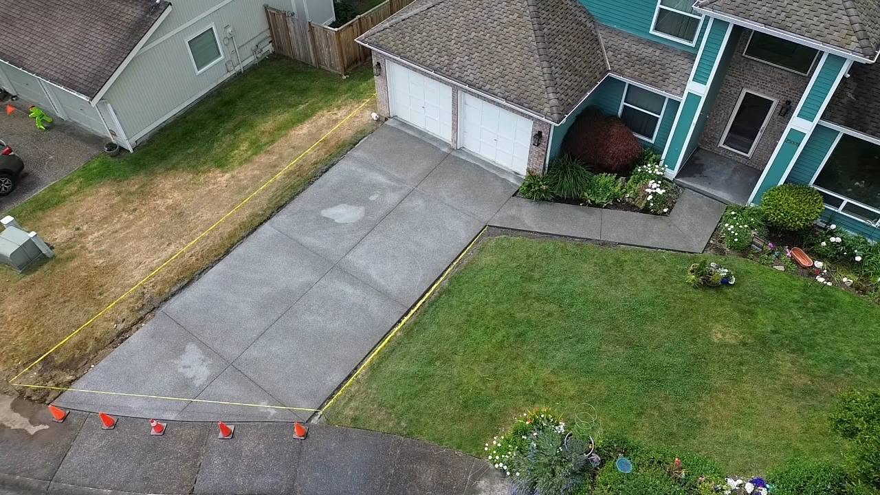 Completed driveway with teal house and traffic cones